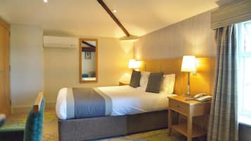 A hotel room with a bed, bedside lamps, a telephone, and a window with curtains.