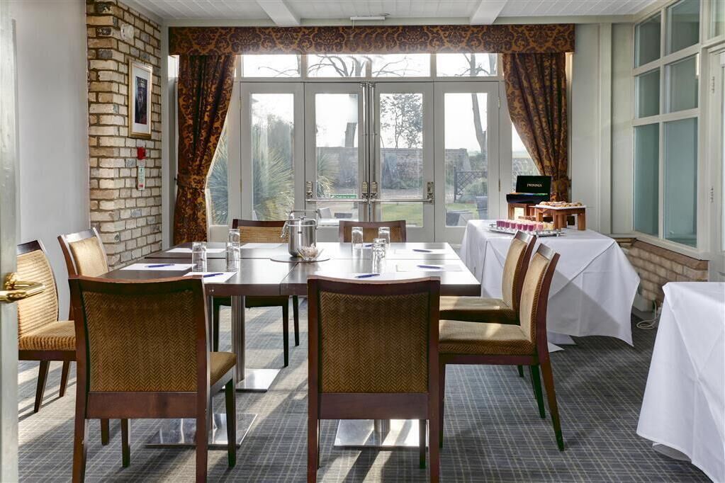 A dining area with a brick wall, large windows, and a view of the outdoors.