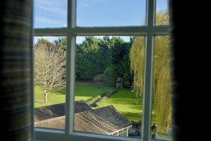 A view through a window of a house with a lawn, a gazebo, and a tree. - Cambridge Quy Mill Hotel & Spa in Cambridge (Cambridge)