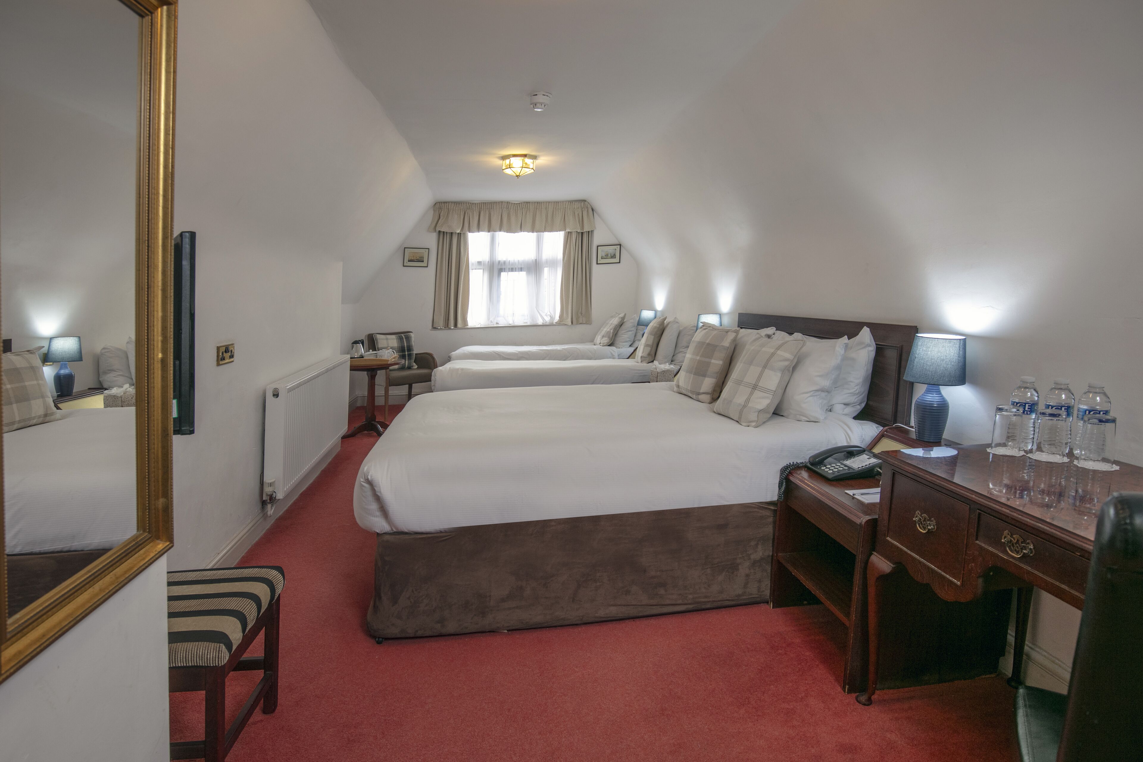 Una camera d'albergo con un letto grande, una scrivania con il telefono e uno specchio.