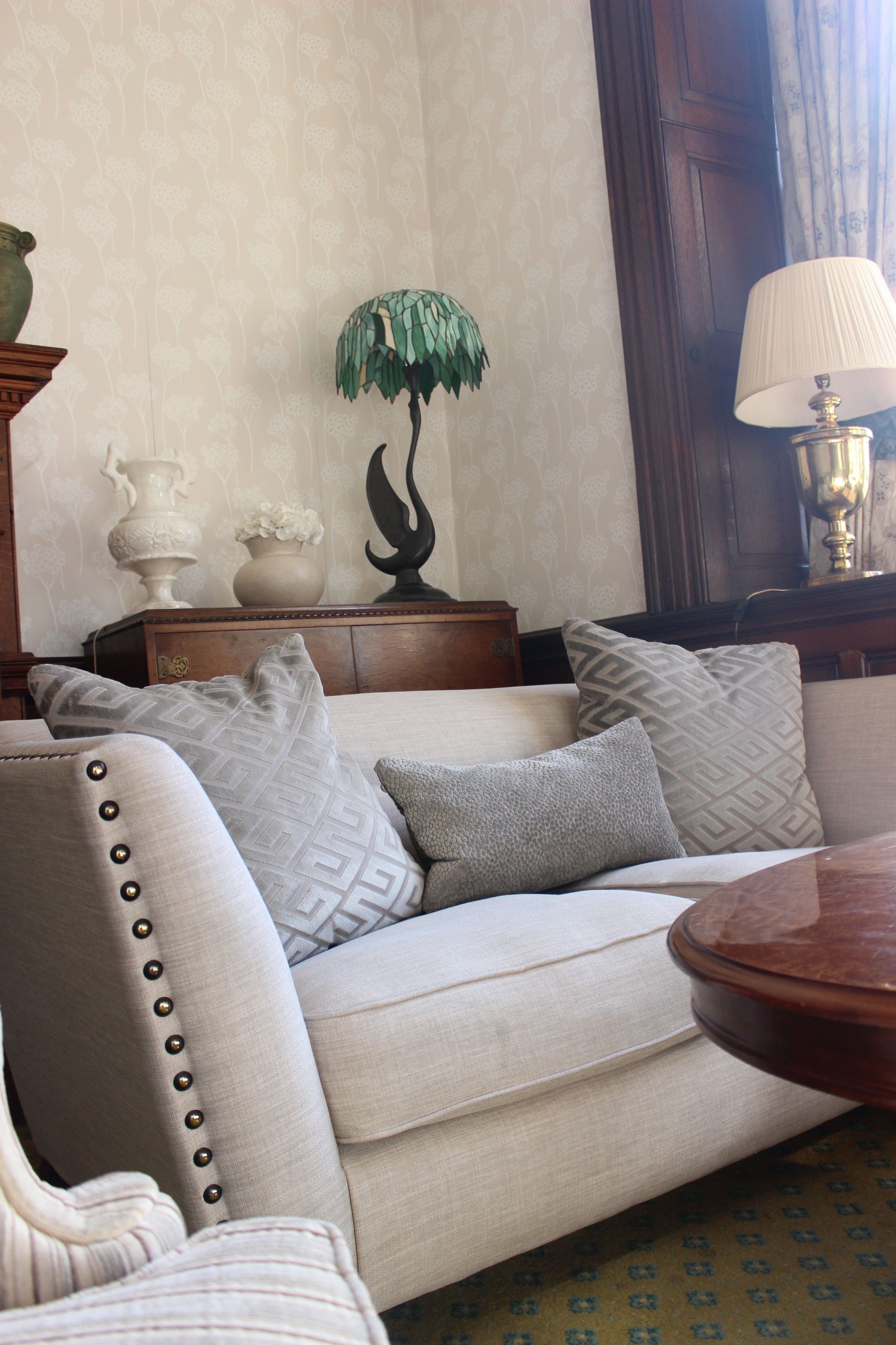 A living room with a sofa, decorative pillows, a lamp, and a wooden side table.