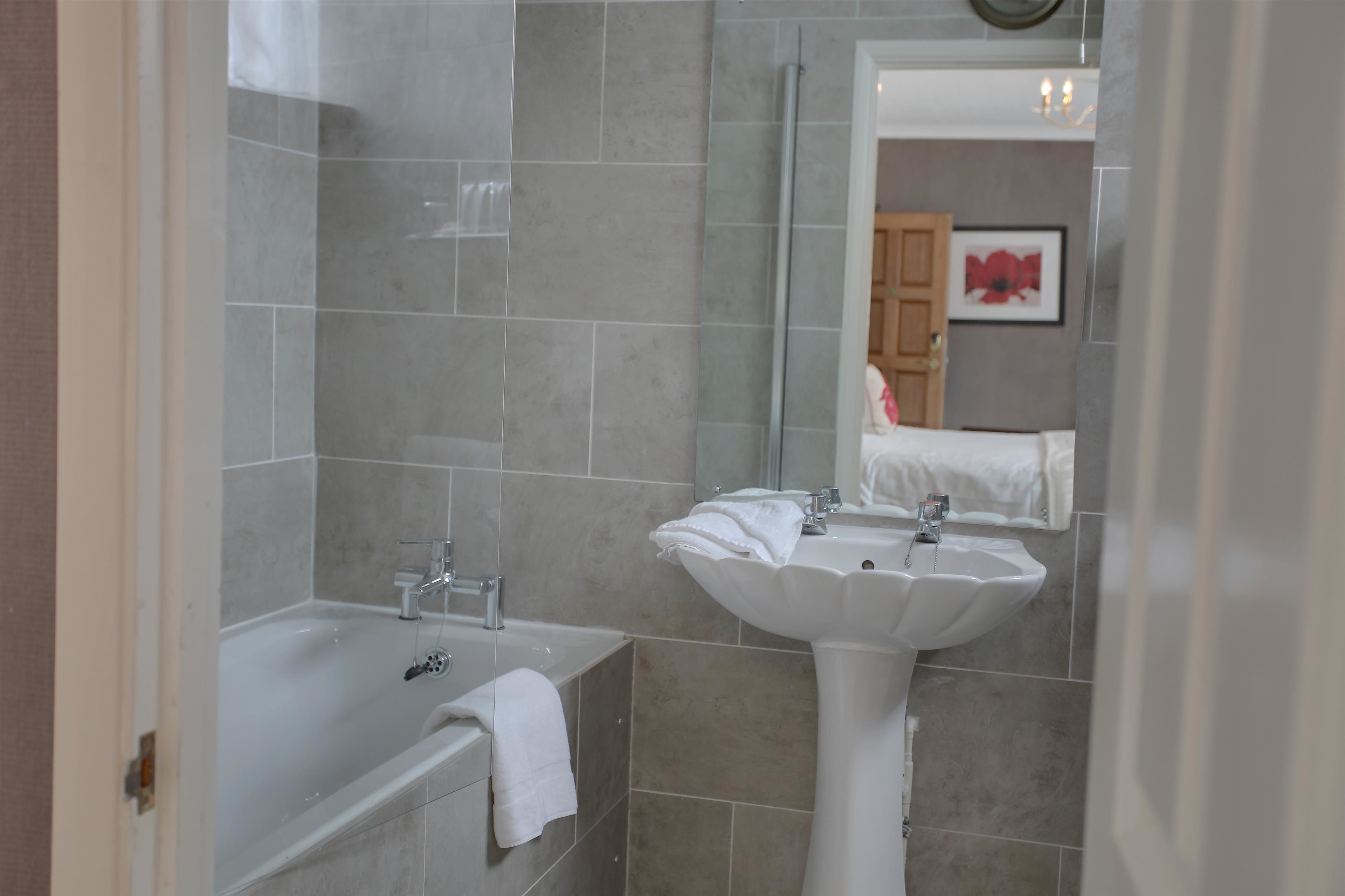 A bathroom with a bathtub, a sink, and a mirror.
