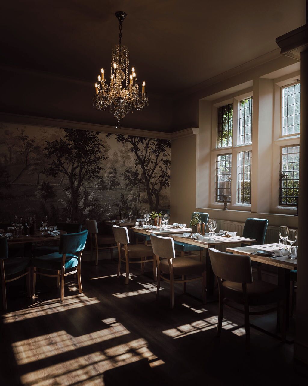 Una sala da pranzo con un lampadario, ampie finestre e un affresco sulla parete.