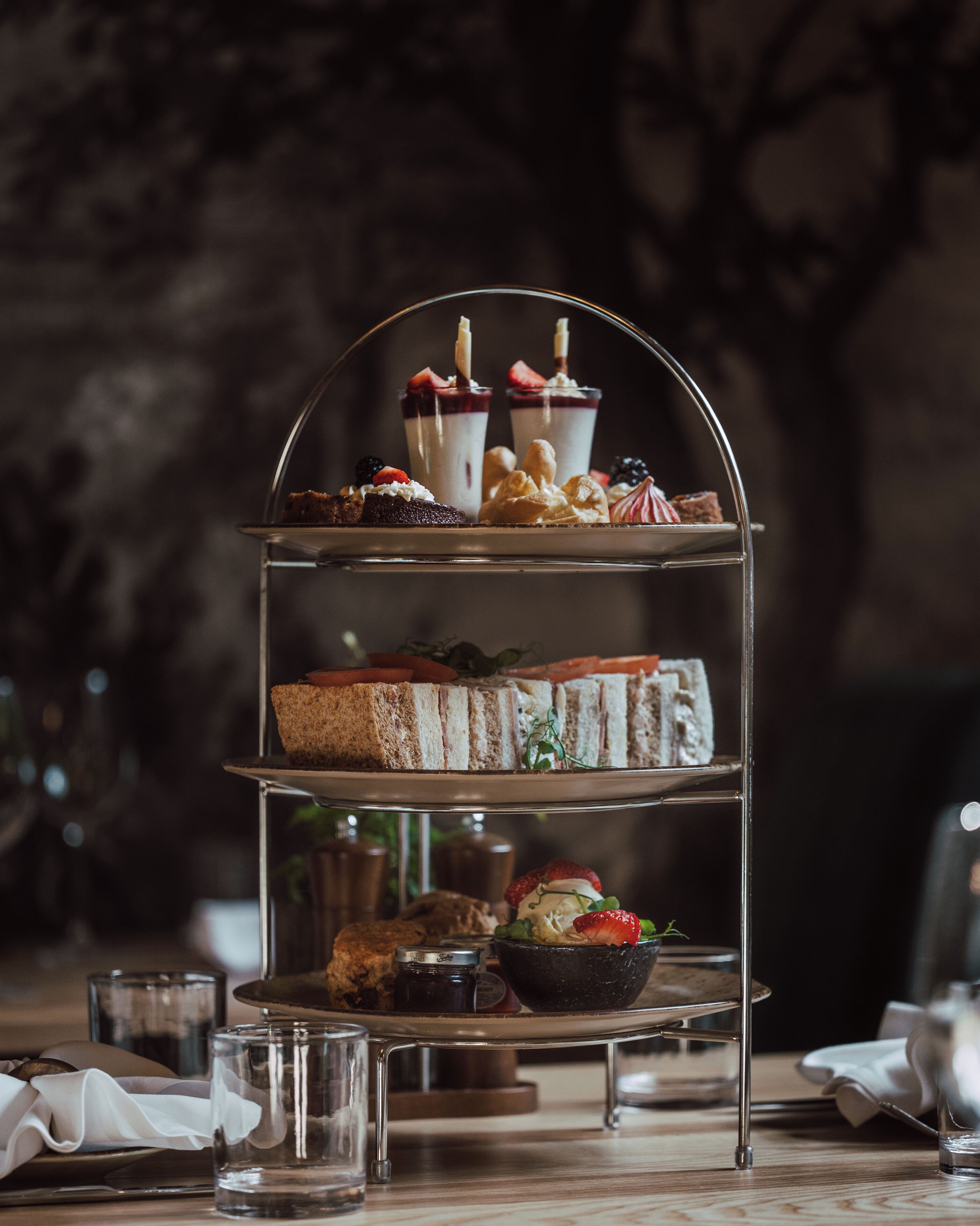 A tiered dessert stand with various pastries and sandwiches.
