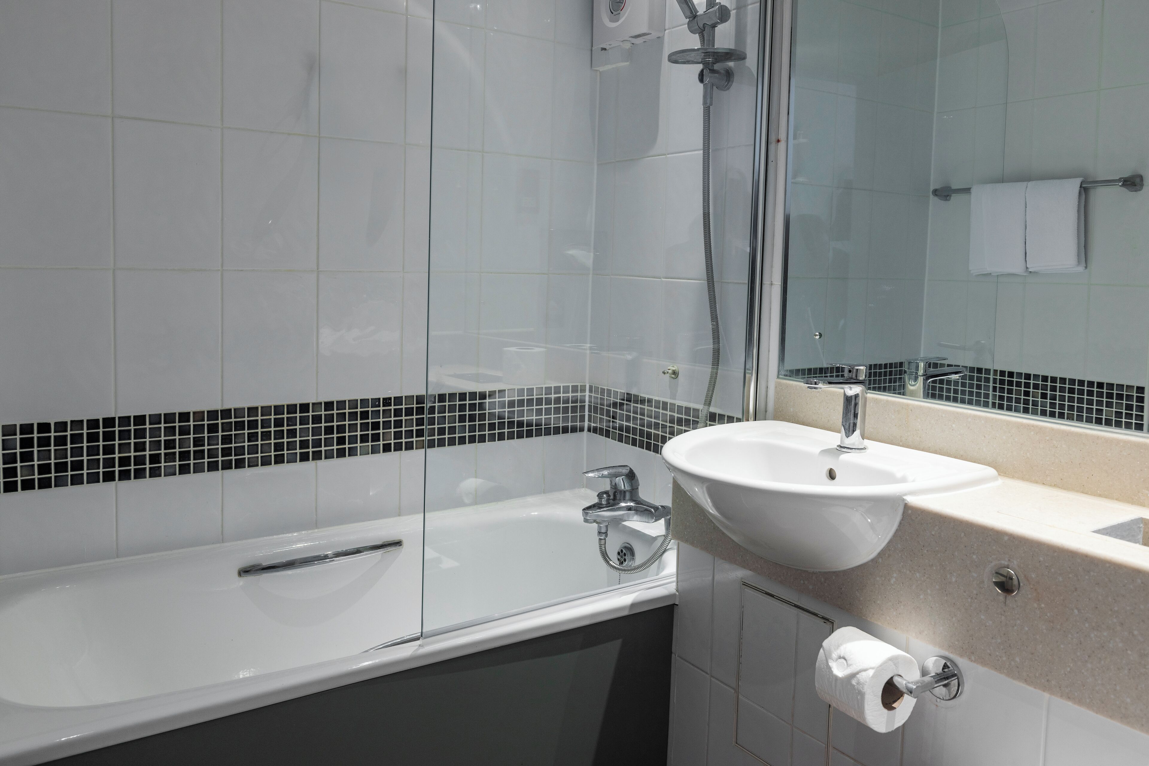 A modern bathroom with a glass-enclosed shower, a white sink, and a mirror.