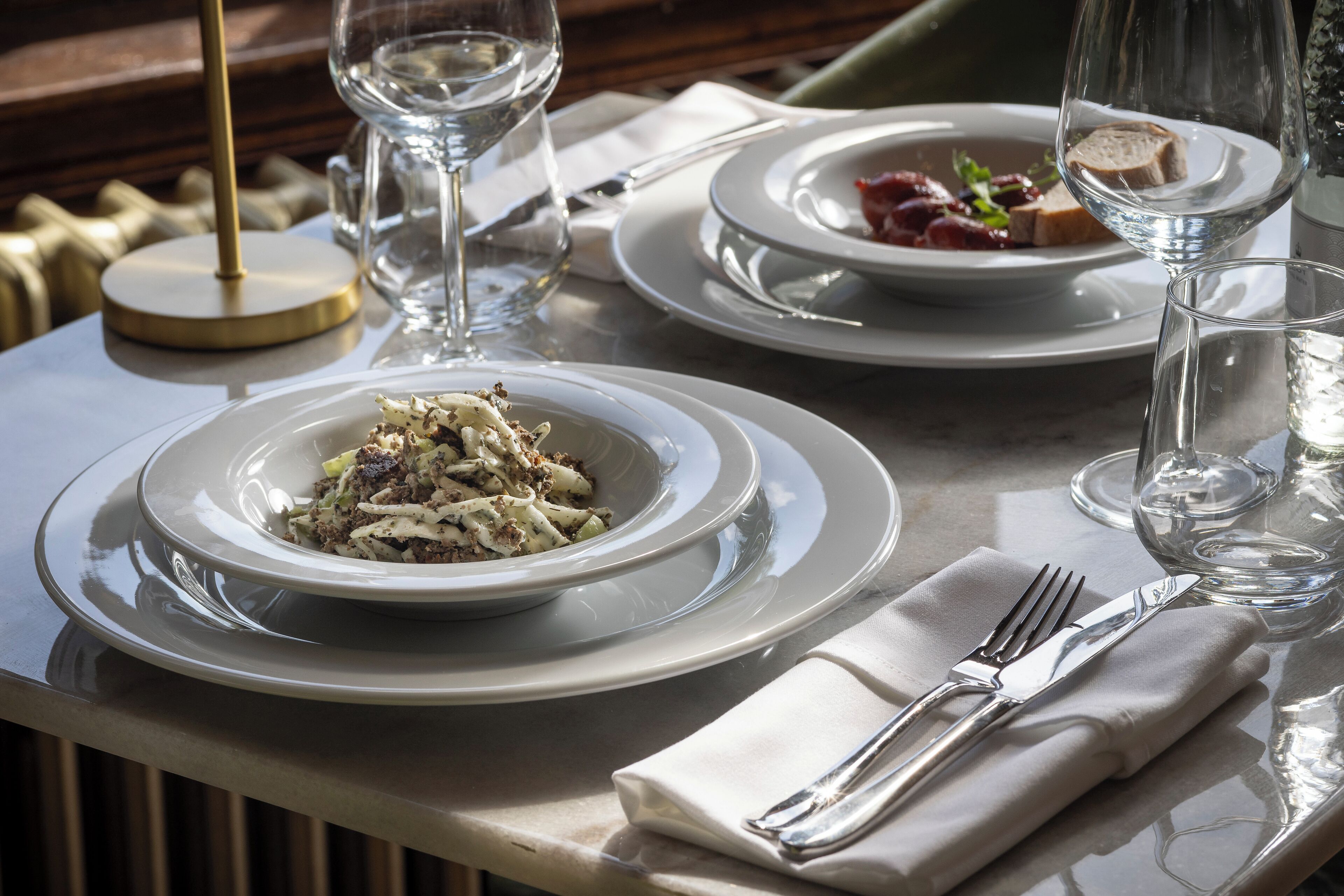 A dining table with plates of food, glasses, and cutlery.