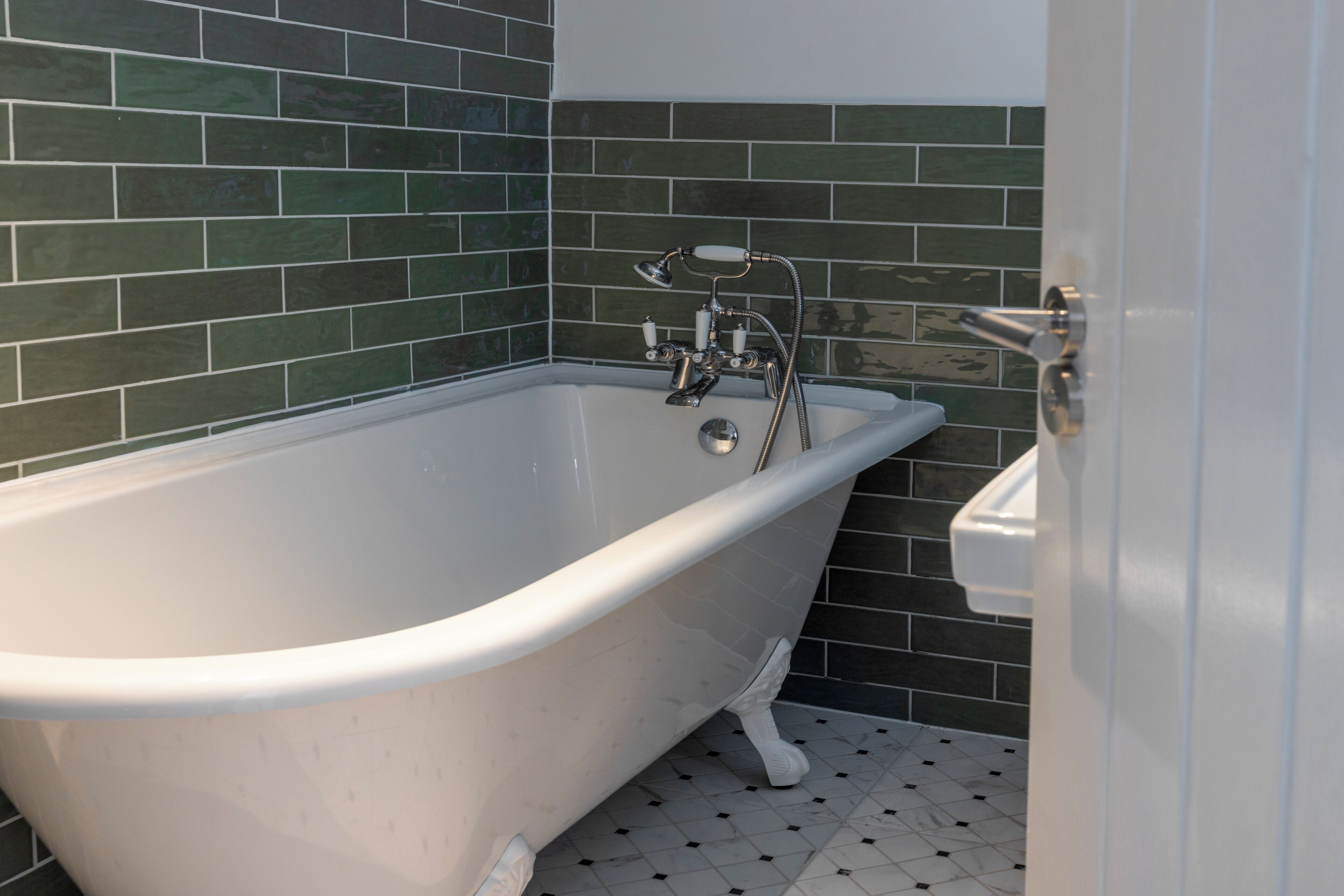 A bathroom with a freestanding bathtub, a showerhead, and a white sink.