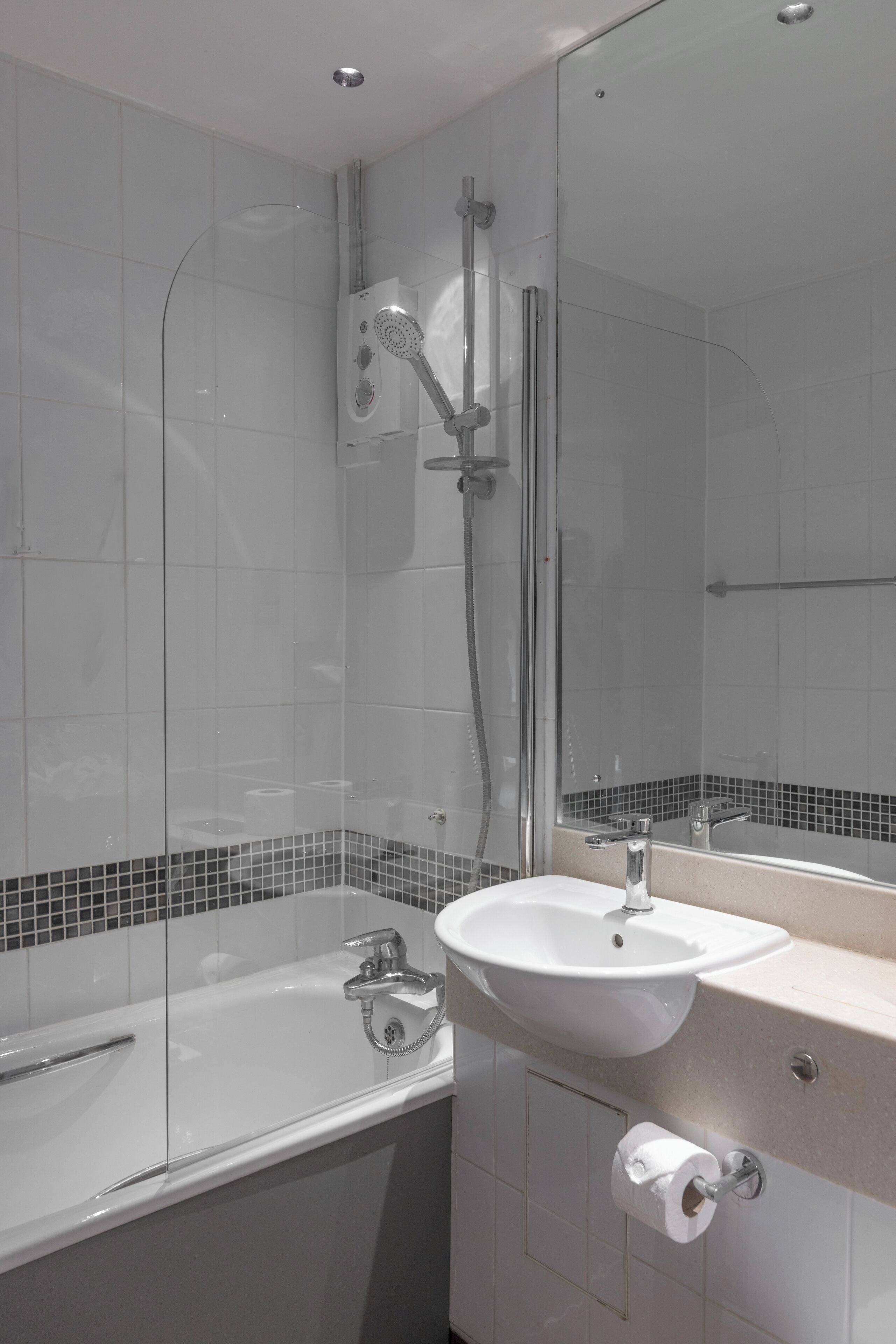 A modern bathroom with a glass-enclosed shower, a white sink, and a mirror.