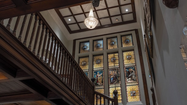 Una imponente escalera con barandilla de madera y un candelabro.