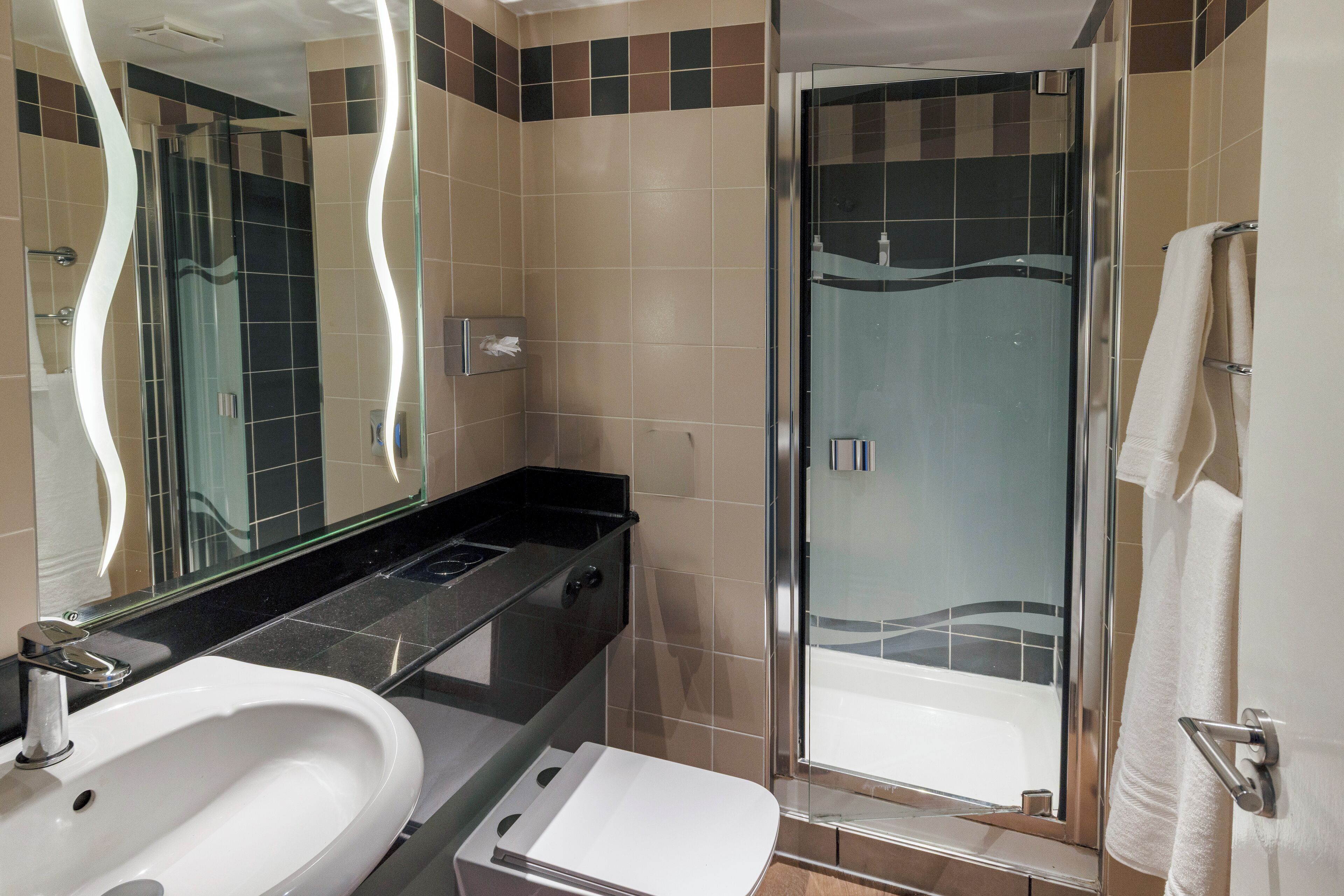 A bathroom with a sink, mirror, and shower.