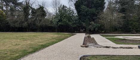 A park with gravel paths, green grass, and trees.