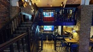 Un restaurant à plusieurs niveaux, doté d’un escalier, de tables et de chaises en bois.