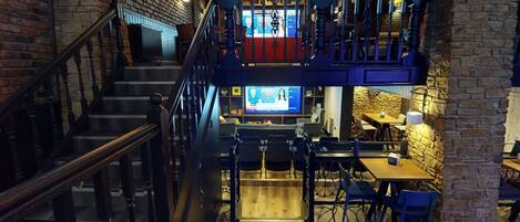 Ein mehrstöckiges Restaurant mit Treppe, Holztischen und -stühlen.