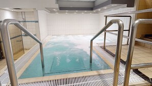 Un espace avec un bain à remous, doté de rampes en métal et de murs carrelés.