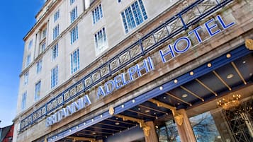 Un edificio histórico con un gran letrero que dice 'Britannia Adelphi Hotel'. Presenta arquitectura clásica con columnas y grandes ventanales.