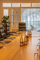 A conference room with a long table, leather chairs, and a potted plant.