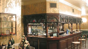 Zona de bar con mostrador, taburetes y una exhibición de botellas.