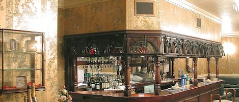 A bar area with a counter, bar stools, and a display of bottles.