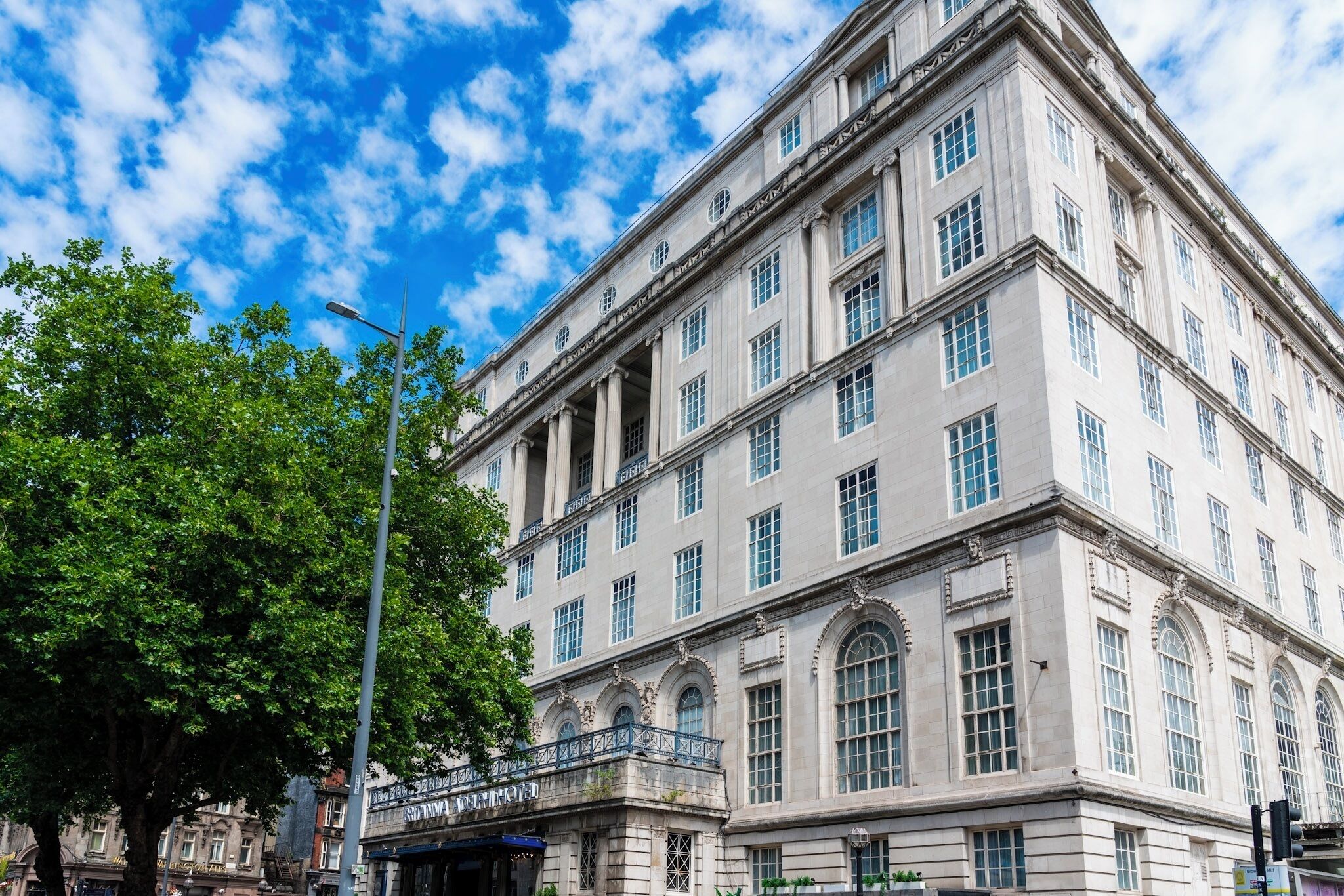 A large, historic building with multiple floors, large windows, and a prominent entrance with a balcony.