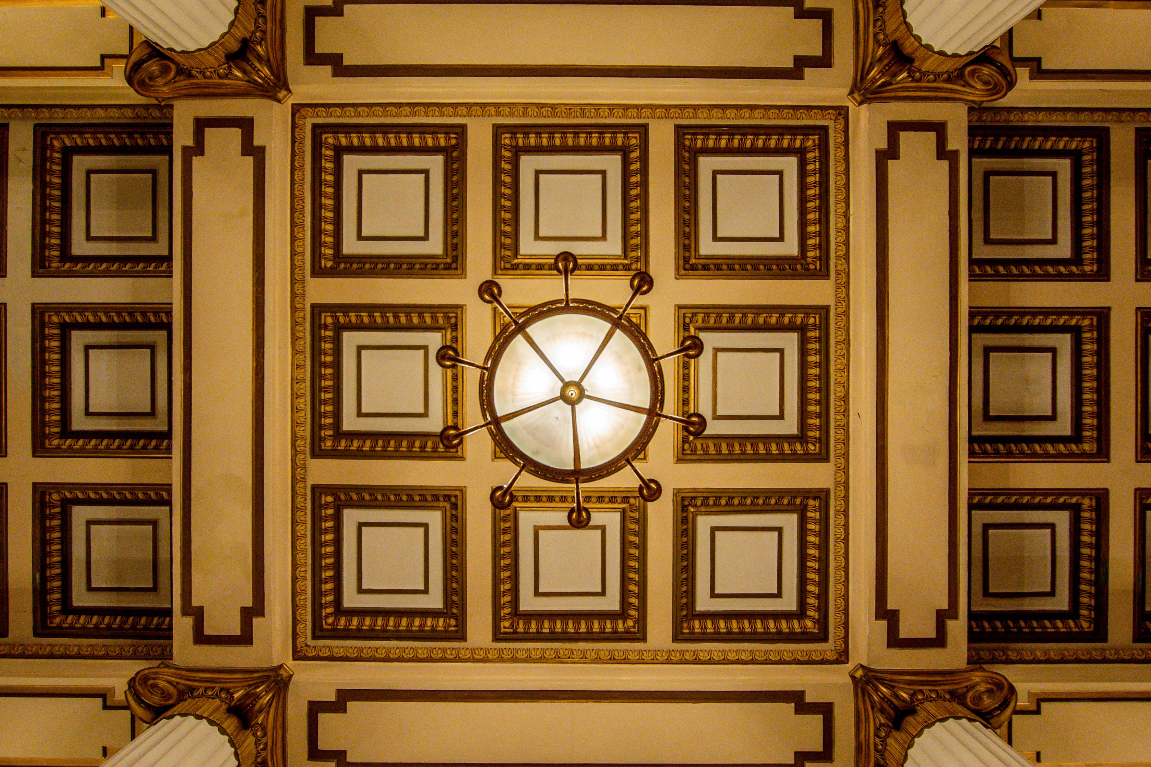 A ceiling with a central circular light fixture surrounded by eight square panels, each with a mirror.