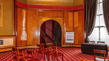 A conference room with wooden paneling, a red carpet, and a whiteboard.