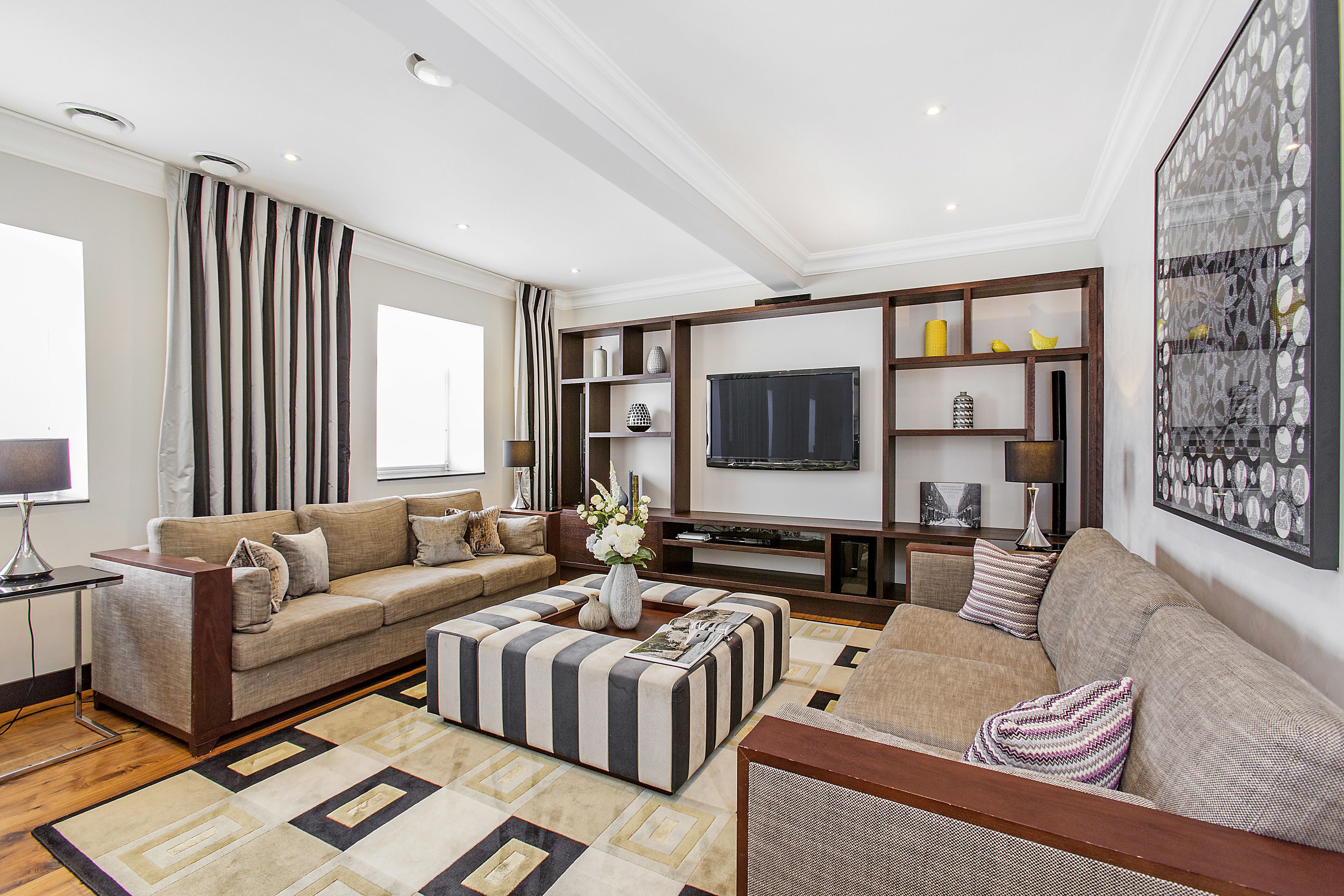 Een moderne woonkamer met een bank, poef en een tv-meubel.