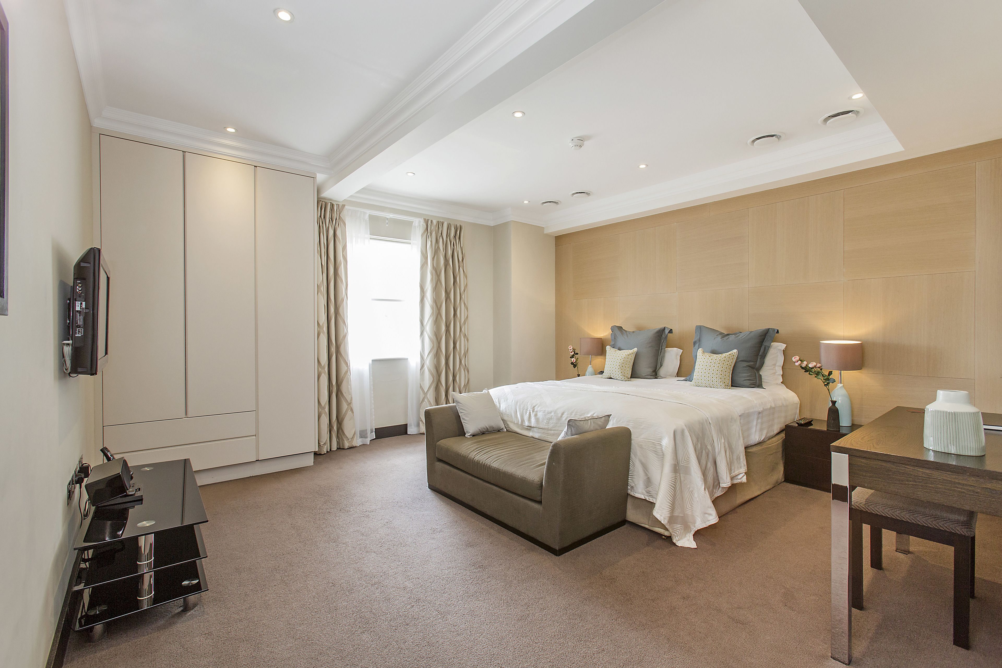 A hotel room with a bed, a sofa, a desk, and a wardrobe.