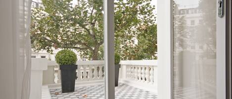 A balcony with a checkered floor, white balustrade, and a potted plant.
