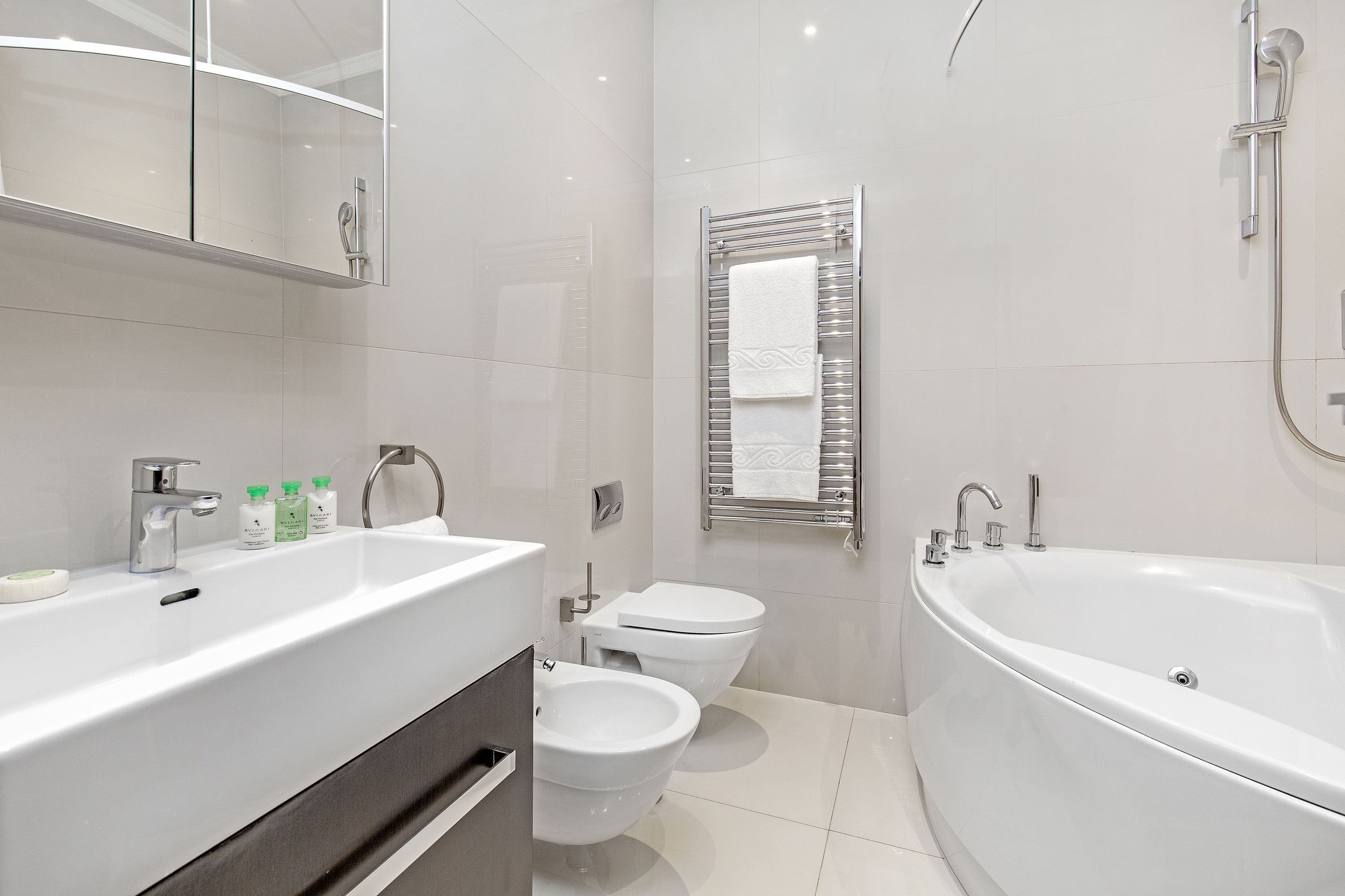 A modern bathroom with a large bathtub, a separate toilet, and a vanity with a mirror.