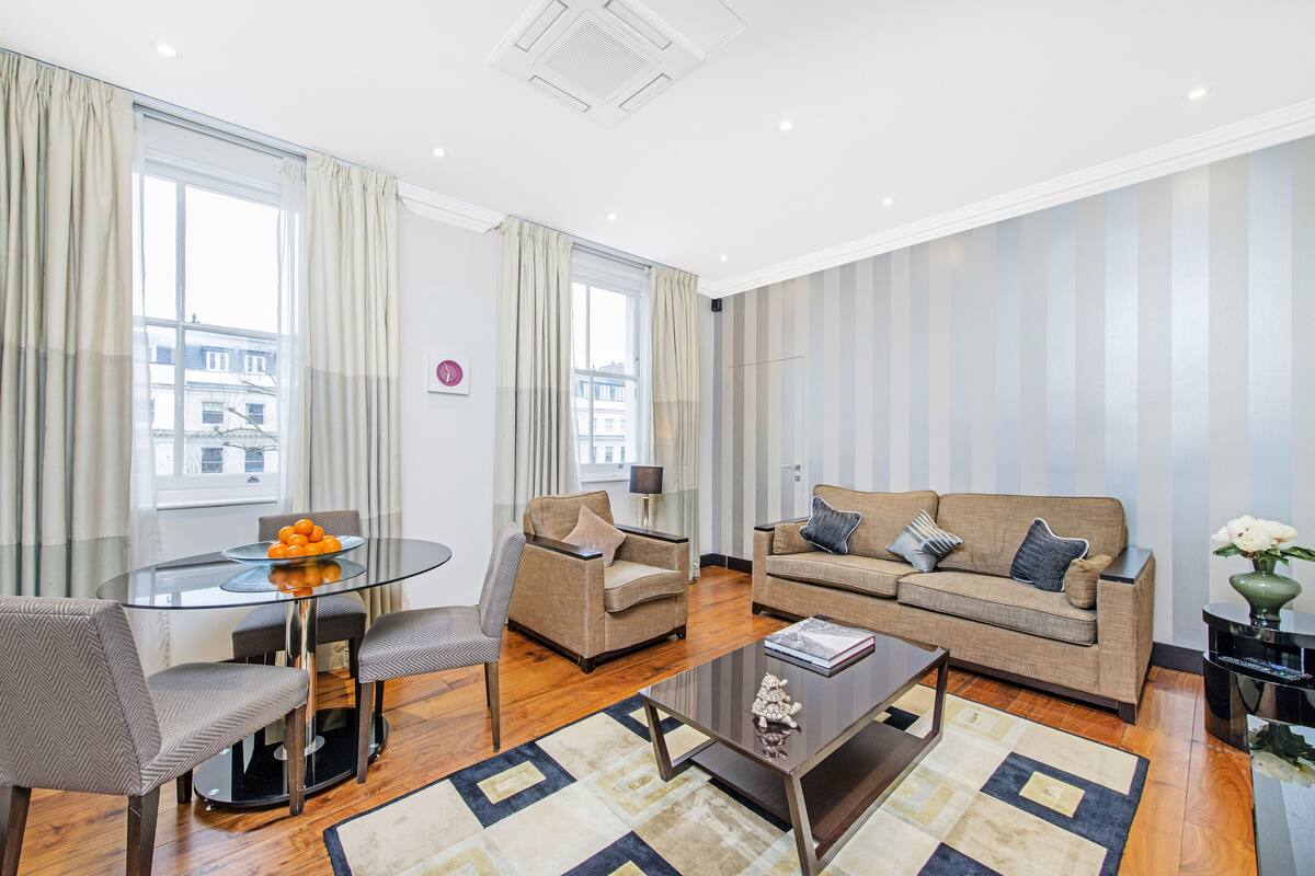 A modern living room with a glass dining table, two sofas, and a coffee table.