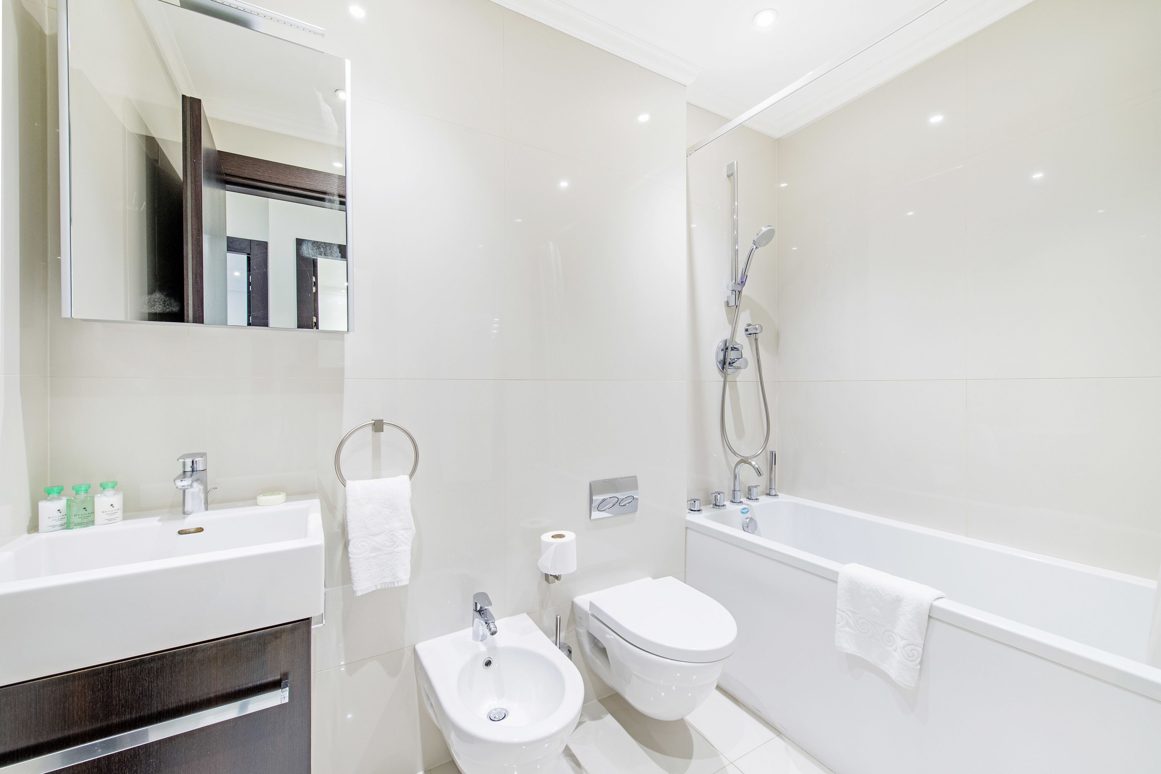 A modern bathroom with a sink, bidet, toilet, and bathtub.