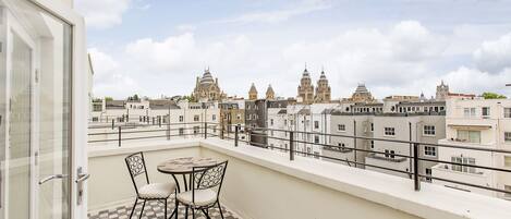 Ein Balkon mit kariertem Boden, zwei Stühlen und einem Tisch.