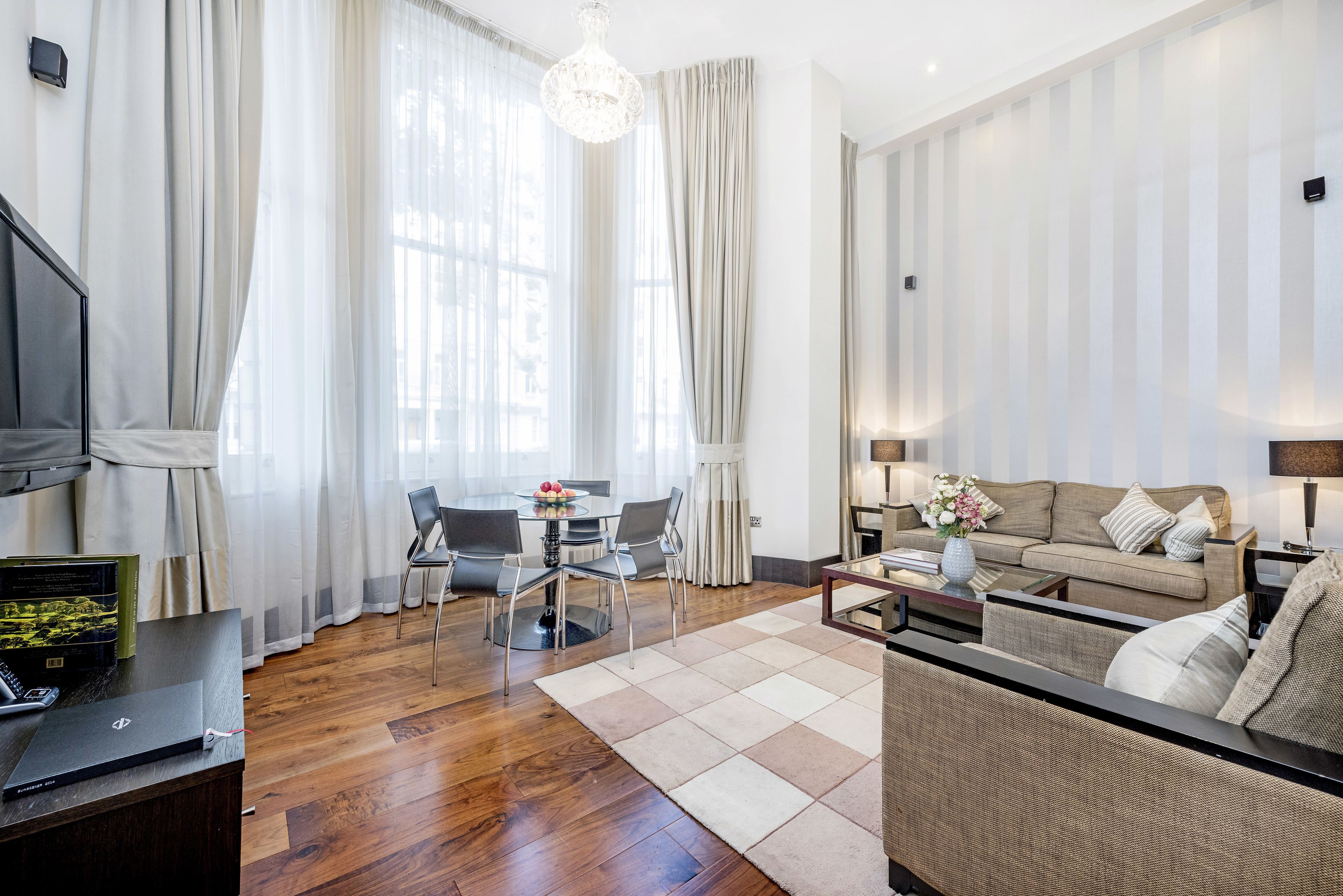 Un salon moderne avec un canapé, une table à manger et des chaises, ainsi qu’un ordinateur portable posé sur un bureau.