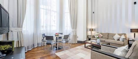 Un salon moderne avec un canapé, une table à manger et des chaises, ainsi qu’un ordinateur portable posé sur un bureau.