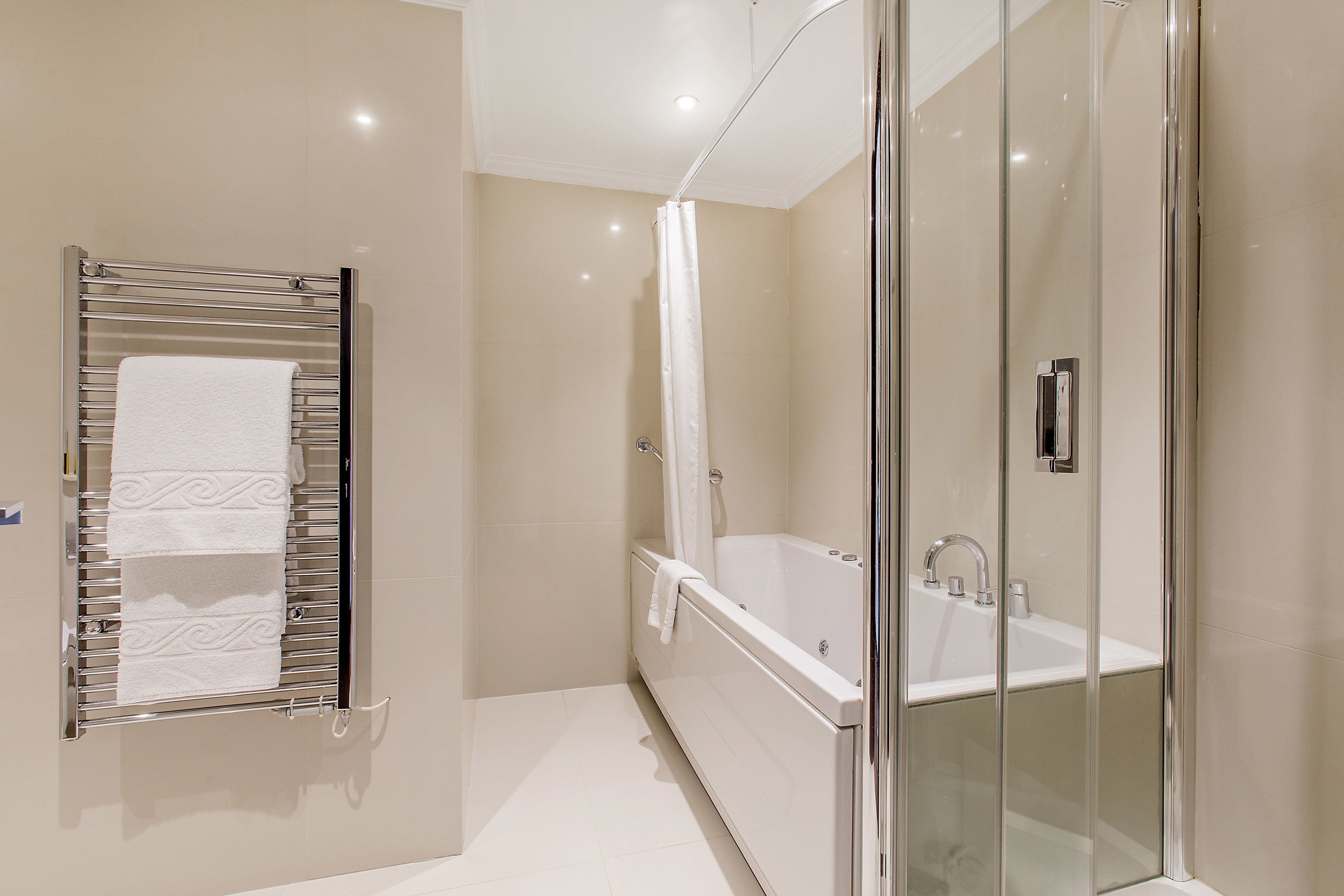 A modern bathroom with a glass-enclosed shower, a freestanding bathtub, and a towel rack with multiple towels.