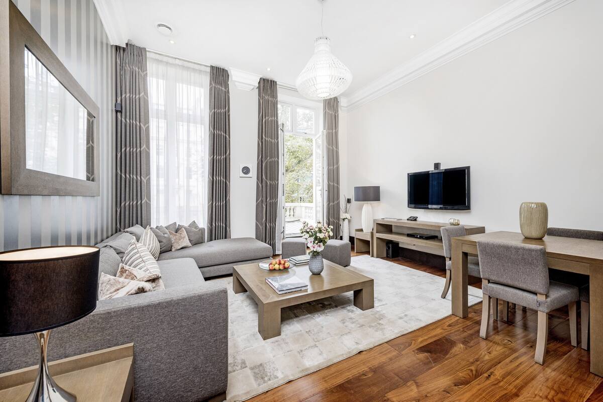 A modern living room with a sofa, coffee table, TV, and dining area.