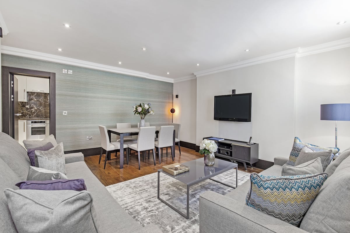 A modern living room with a sofa, coffee table, and a dining area with chairs and a table.