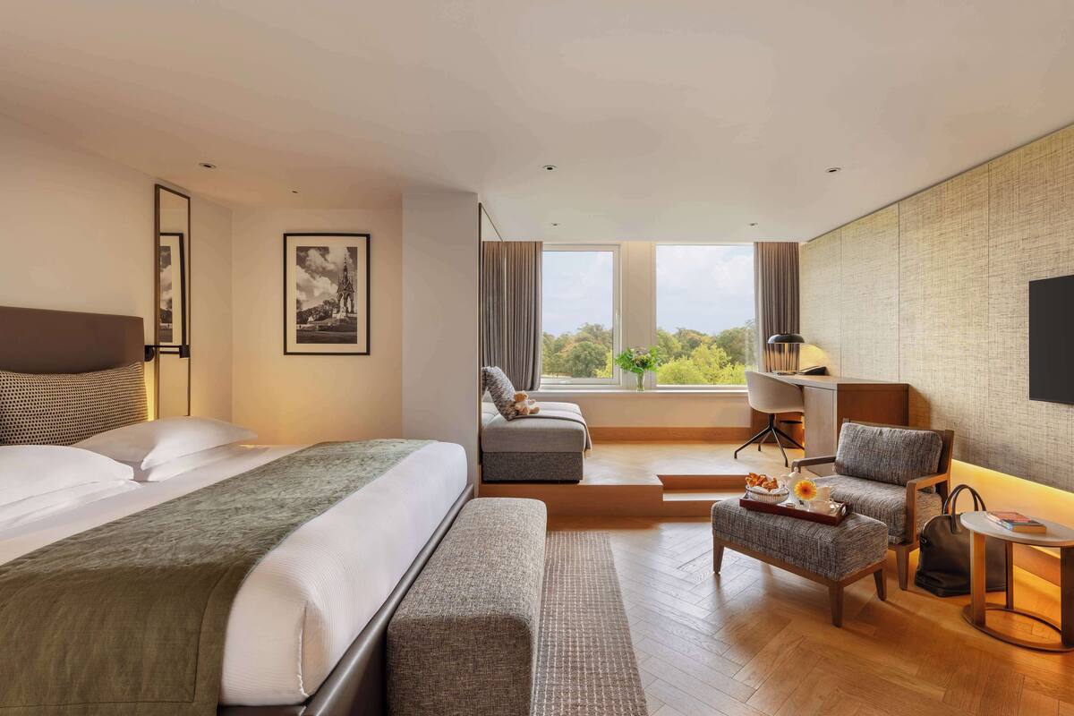 Une chambre d’hôtel avec un lit, un canapé, une chaise, un bureau et une télévision.