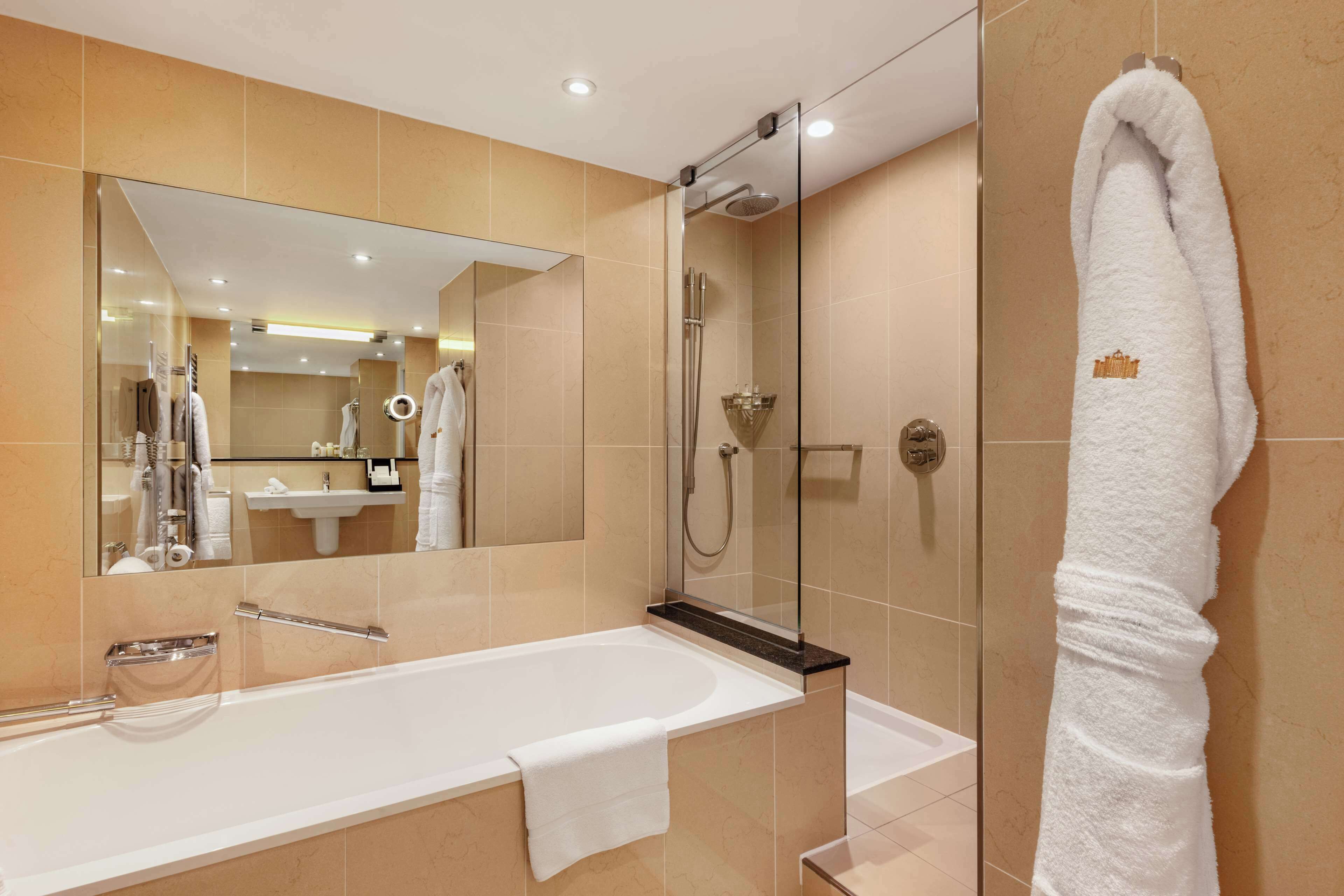 A modern bathroom with a bathtub, shower, and a large mirror.