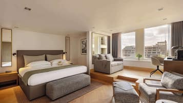Une chambre d’hôtel moderne, dotée d’un grand lit, d’un canapé, d’un bureau et offrant une vue sur la ville.