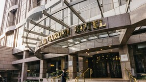 A hotel entrance with a sign reading 'Royal Garden Hotel,' a grand staircase, and a security guard. - Royal Garden Hotel (London)