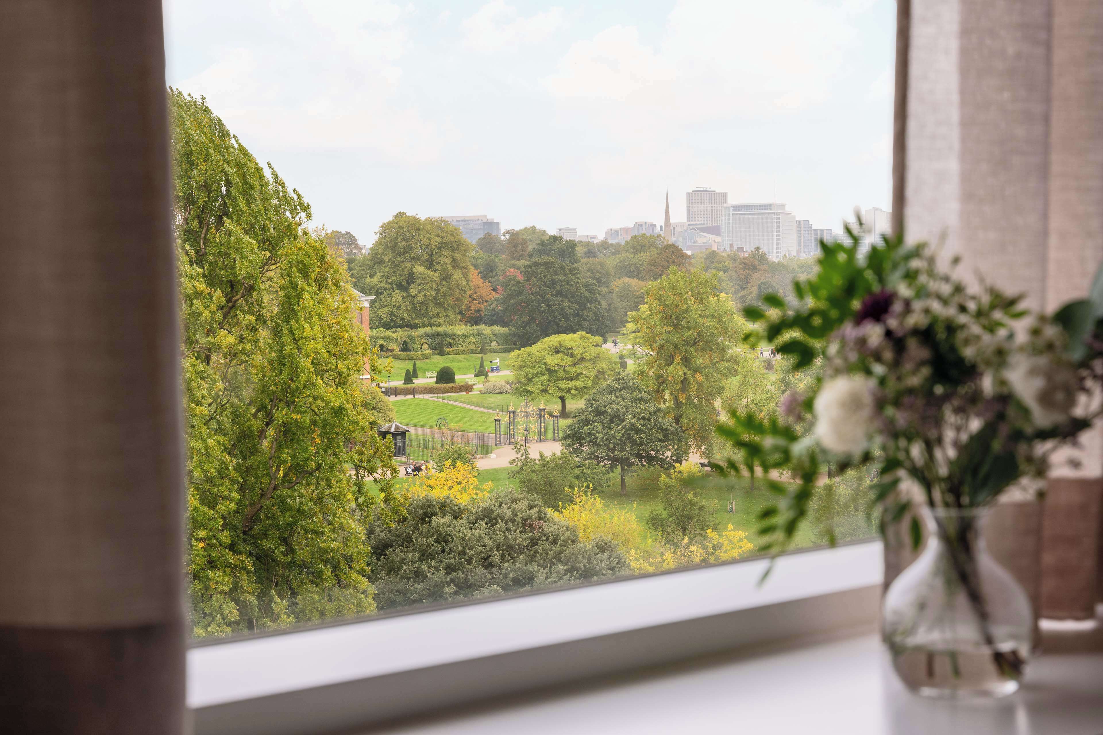 A view through a window with a vase of flowers on a table.