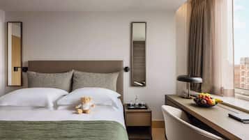 Une chambre d’hôtel comprenant un lit, un bureau, une chaise, une table de chevet, un miroir et une fenêtre avec des rideaux.