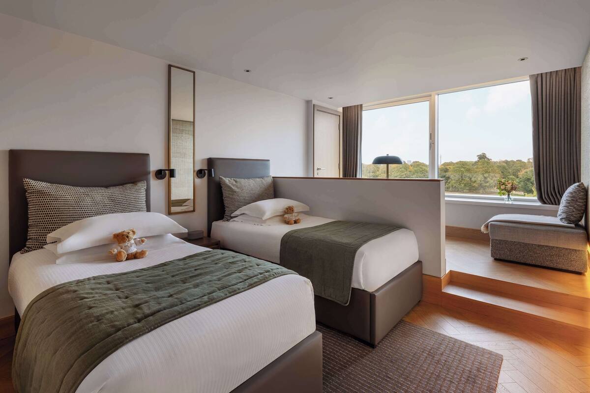 Une chambre d’hôtel avec deux lits, une grande fenêtre donnant sur un beau paysage et un balcon.