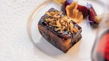 A white plate with a piece of food topped with granola and a small portion of fruit.