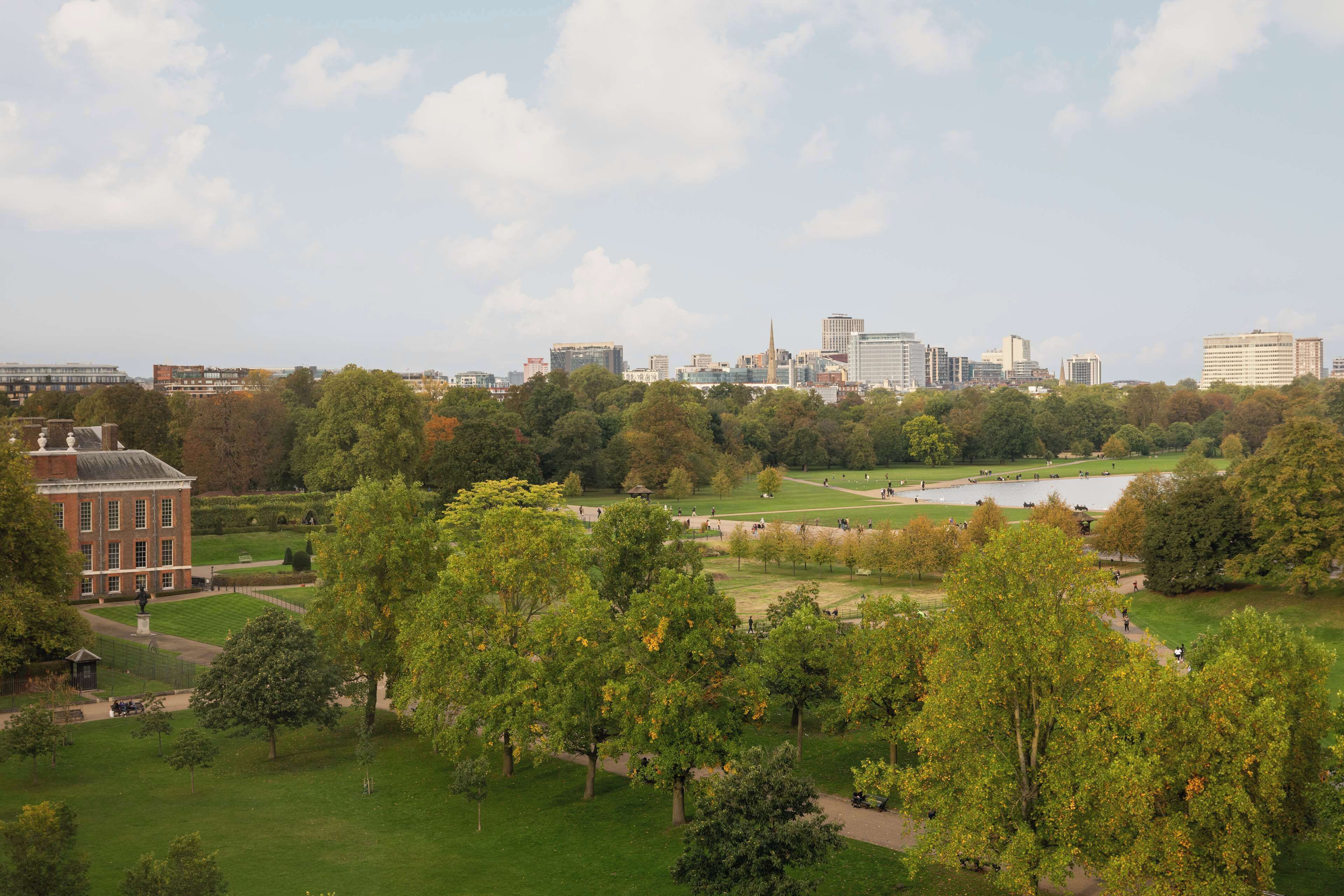A park with a large building in the foreground and a city skyline in the background.