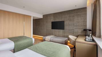 Quarto de hotel com duas camas, uma escrivaninha, uma cadeira, televisão de tela plana e guarda-roupa.