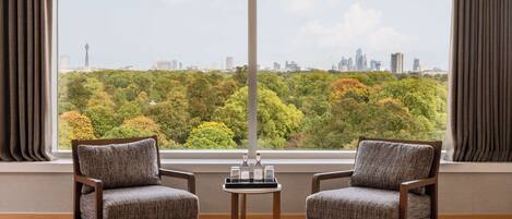 A room with two chairs, a small table, and a large window with a cityscape view.