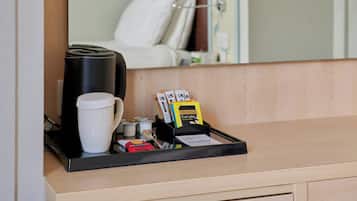 En hotelreception med en kaffemaskine, en hvid kop, en bakke med en ske, en kortoplægger med et kort og en lille æske.