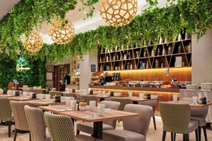 A restaurant with tables, chairs, hanging lights, and a bar area.